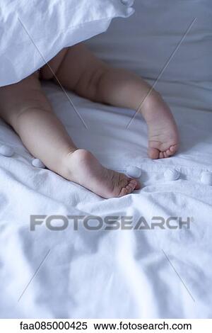 Stock Photography - Baby's barefeet under duvet, cropped. Fotosearch