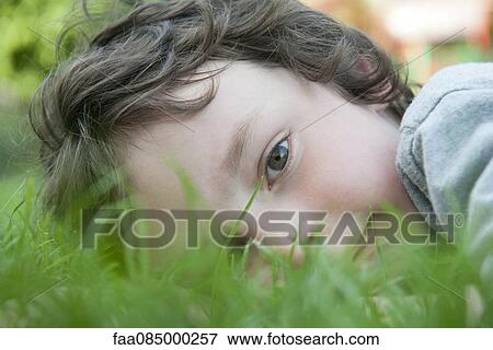 Stock Photo - Boy lying in grass, portrait. Fotosearch