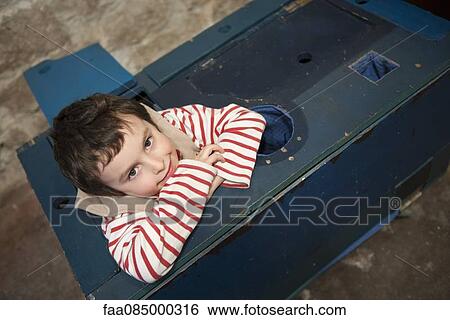 Stock Photograph - Boy resting head on arms, portrait. Fotosearch