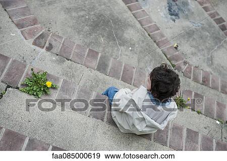 Boy sitting alone on steps, looking away in thought View Large Photo Image Stock Photo - Boy sitting alone on steps, looking away in thought. Fotosearch