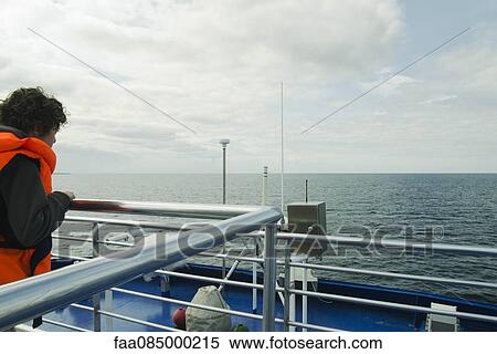 Stock Photography - Boy watching the horizon, on the upper deck of a boat. Fotosearch