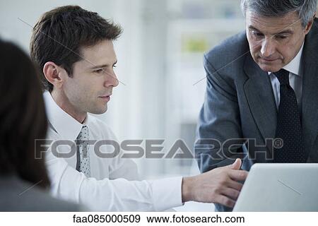 Business associates collaborating with laptop computer View Large Photo Image Stock Photo - Business associates collaborating with laptop computer. Fotosearch