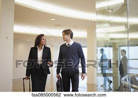 Business associates walking and talking together in corridor View Large Photo Image Stock Image - Business associates walking and talking together in corridor. Fotosearch