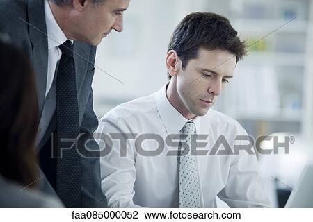 Stock Image - Business associates working together in office. Fotosearch