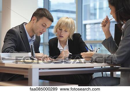 Business people reviewing contract while meeting with female excutive View Large Photo Image Stock Photo - Business people reviewing contract while meeting with female excutive. Fotosearch