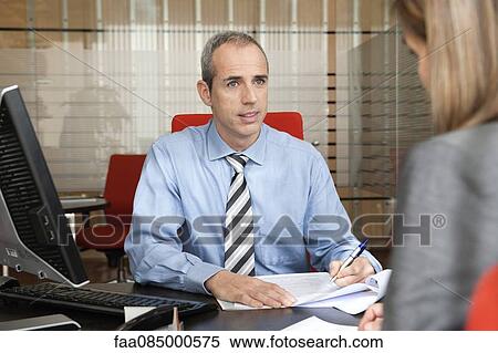 Stock Photography - Businessman assisting client in office. Fotosearch