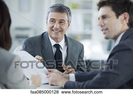 Businessman discussing document with colleagues View Large Photo Image Stock Photo - Businessman discussing document with colleagues. Fotosearch