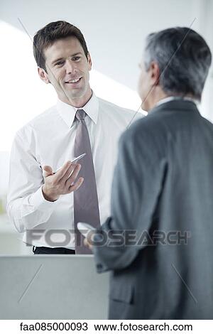 Businessman discussing work with colleague View Large Photo Image Stock Image - Businessman discussing work with colleague. Fotosearch