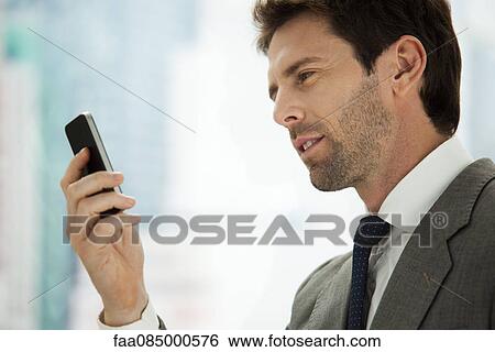 Businessman looking at cell phone View Large Photo Image Stock Photograph - Businessman looking at cell phone. Fotosearch