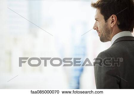 Stock Image - Businessman looking out window, rear view. Fotosearch