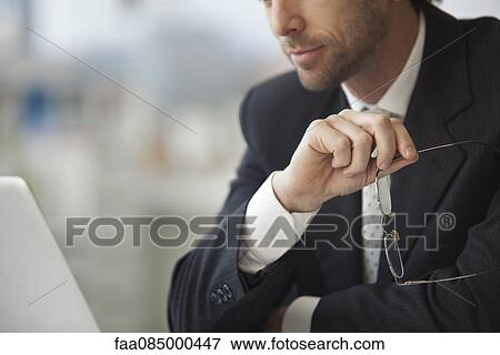 Businessman sitting with glasses in hand, cropped View Large Photo Image Stock Photo - Businessman sitting with glasses in hand, cropped. Fotosearch