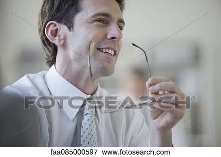 Stock Photo - Businessman smiling and looking away in thought. Fotosearch
