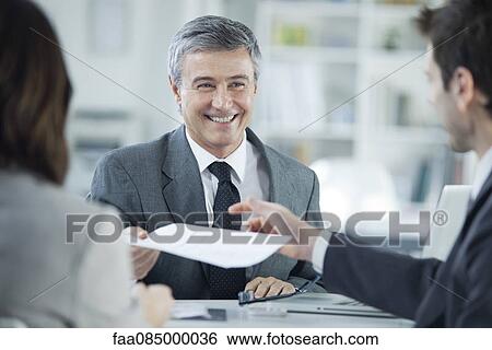 Businessman smiling during meeting with clients View Large Photo Image Stock Photograph - Businessman smiling during meeting with clients. Fotosearch