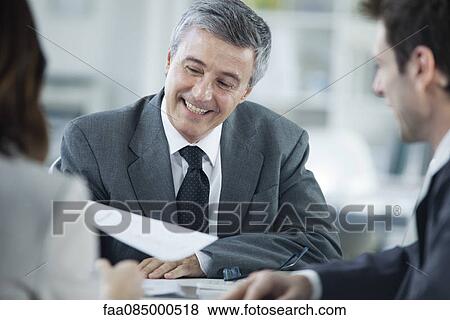 Stock Photo - Businessman smiling in meeting with colleagues. Fotosearch