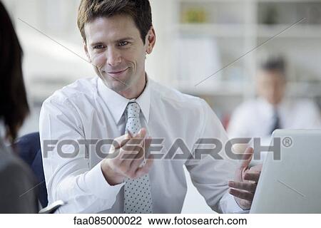 Businessman talking with colleague in office View Large Photo Image Stock Image - Businessman talking with colleague in office. Fotosearch