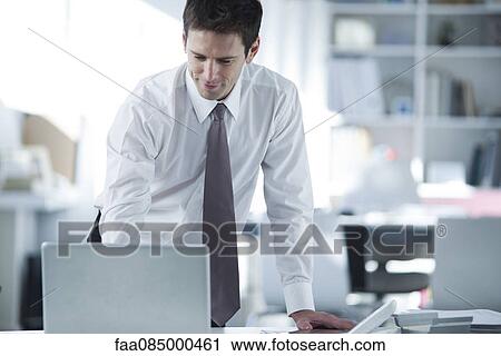 Stock Image - Businessman using laptop computer in office. Fotosearch