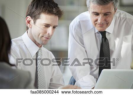 Businessmen collaborating with laptop computer View Large Photo Image Picture - Businessmen collaborating with laptop computer. Fotosearch