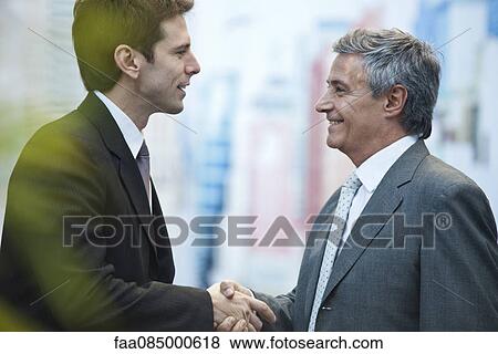 Stock Photo - Businessmen shaking hands outdoors. Fotosearch