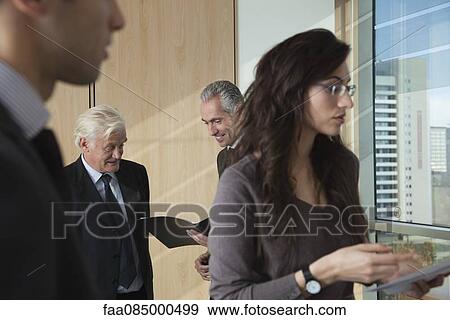 Colleagues discussing documents in office View Large Photo Image Stock Photo - Colleagues discussing documents in office. Fotosearch