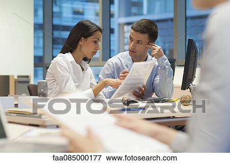 Colleagues discussing work in office, woman working in foreground View Large Photo Image Stock Photo - Colleagues discussing work in office, woman working in foreground. Fotosearch