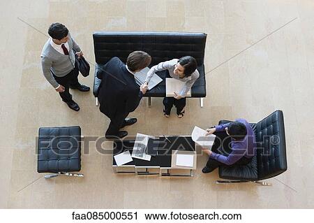 Stock Image - Colleagues shaking hands in meeting, overhead view. Fotosearch