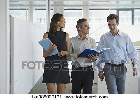 Colleagues walking and discussing documents together View Large Photo Image Stock Image - Colleagues walking and discussing documents together. Fotosearch