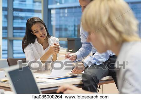 Picture - Colleagues working together in office, woman working in foreground. Fotosearch