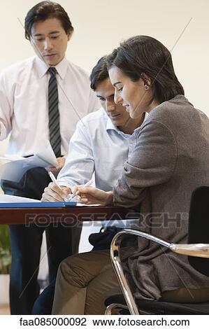 Stock Image - Colleagues working together in office. Fotosearch