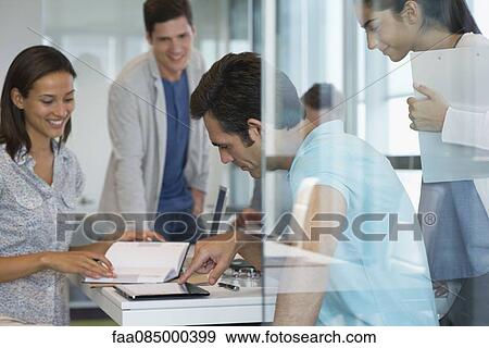 Stock Photo - Colleagues working together in office, one using digital tablet. Fotosearch