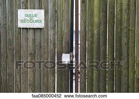 Stock Image - Emergency exit sign on wooden gate. Fotosearch