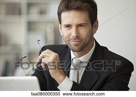 Stock Image - Executive holding glasses, portrait. Fotosearch