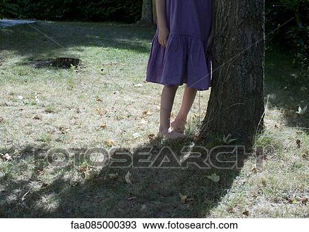 Girl leaning against tree trunk, cropped View Large Photo Image Stock Image - Girl leaning against tree trunk, cropped. Fotosearch
