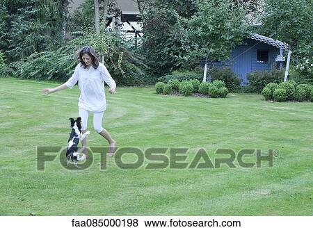 Stock Photo - Girl playing with pet dog in backyard. Fotosearch