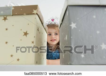Stock Image - Girl with tiara in front of gift boxes. Fotosearch