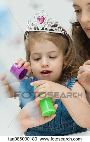 Stock Image - Girl with tiara preparing to blow bubbles. Fotosearch