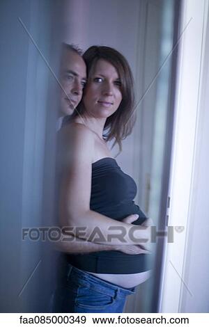 Stock Photo - Husband wrapping arms around pregnant wife. Fotosearch