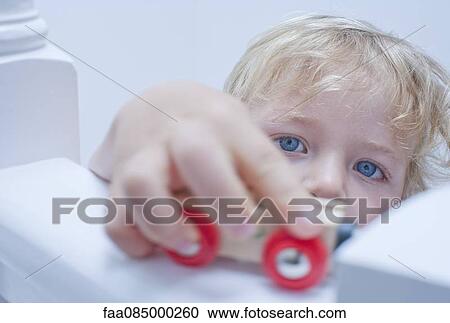 Stock Image - Little boy playing toy car on banister. Fotosearch