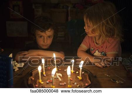 Little boy preparing to blow out candles on birthday cake as younger sister watches View Large Photo Image Stock Photo - Little boy preparing to blow out candles on birthday cake as younger sister watches. Fotosearch