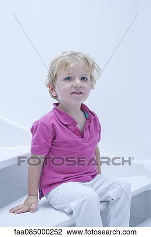 Stock Image - Little boy sitting on stairs, portrait. Fotosearch