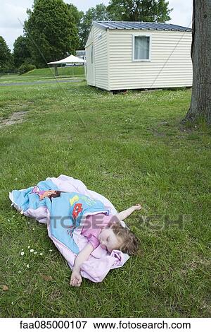 Stock Photo - Little girl napping in sleeping bag on grass. Fotosearch