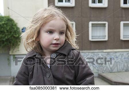 Stock Image - Little girl outdoors, looking away. Fotosearch
