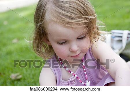 Picture - Little girl outdoors, looking down. Fotosearch