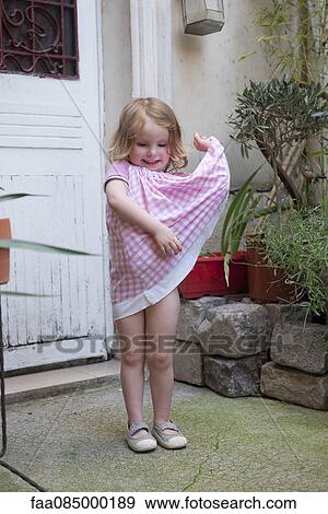 Stock Photo - Little girl playing with dress, portrait. Fotosearch