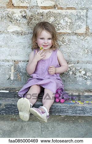 Stock Photo - Little girl sitting on curb, portrait. Fotosearch