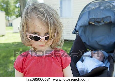 Stock Image - Little girl wearing sunglasses, portrait. Fotosearch