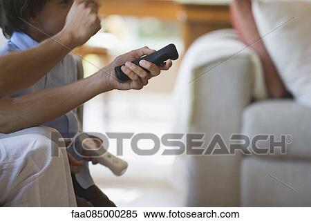 Stock Photography - Man and child playing video game using remote controls, cropped. Fotosearch