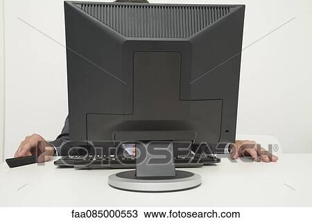 Stock Image - Man sitting in front of computer monitor. Fotosearch