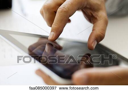 Stock Photo - Man using touch screen on digital tablet, cropped. Fotosearch
