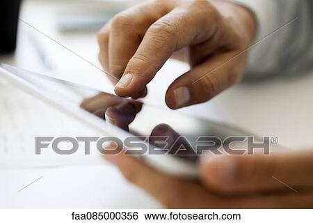 Stock Photograph - Man using touch screen on digital tablet, cropped. Fotosearch