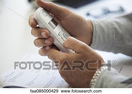 Stock Photo - Man's hands holding cell phone, cropped. Fotosearch